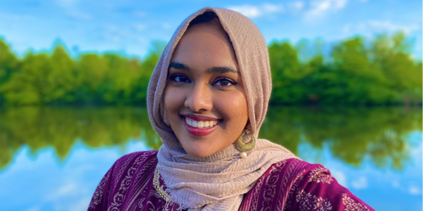 Fyzah Islam smiles at the camera as she wears a headscarf and gold earring.