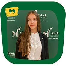 Gabriella Grabovska stands smiling in front of a green background with the Schar School of Policy and Government logo on it