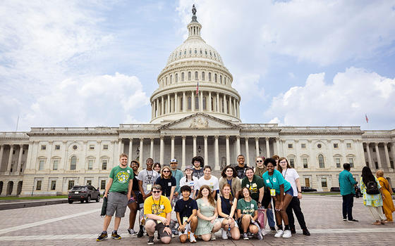 A group of teens in tee shirts pose in front of the Capitol building.